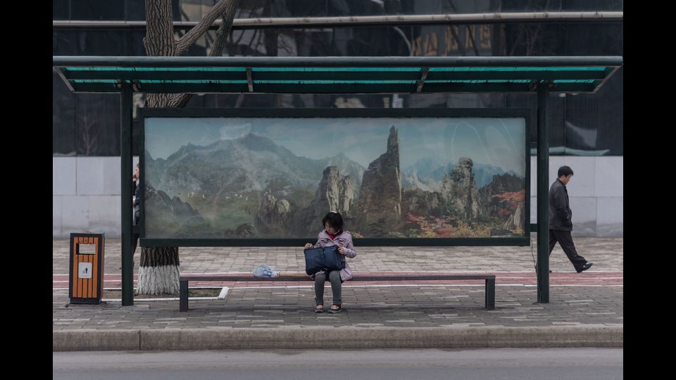 Una bambina aspetta l'autobus alla fermata. A Pyongyang gli autobus sono di gran lunga il mezzo di trasporto pubblico pi&ugrave; comune dove l'uso delle auto private &egrave; raro. I biglietti costano 5 won ciascuno, meno di 0,1 centesimi di dollaro al tasso di libero mercato, rendendo i viaggi praticamente gratuiti