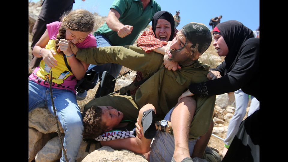 Ahed Tamimi combatte con altri membri della sua famiglia per liberare un ragazzo palestinese detenuto da un soldato israeliano  durante gli scontri tra le forze di sicurezza israeliane e manifestanti palestinesi il 28 agosto 2015, nel villaggio della West Bank di Nabi Saleh vicino a Ramallah (Afp)&nbsp;