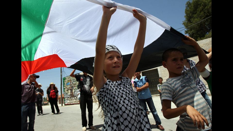 Ahed Tamimi alza la sua bandiera nazionale mentre prende parte a una manifestazione di protesta il 10 giugno 2011, contro l'espropriazione della terra palestinese, nel villaggio di Nabi Saleh, nella Cisgiordania occupata da Israele (Afp)&nbsp;