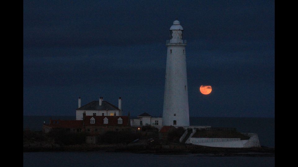 La super Luna rossa e blu vista dal Faro di St. Mary a Whitley Bay nel Regno Unito