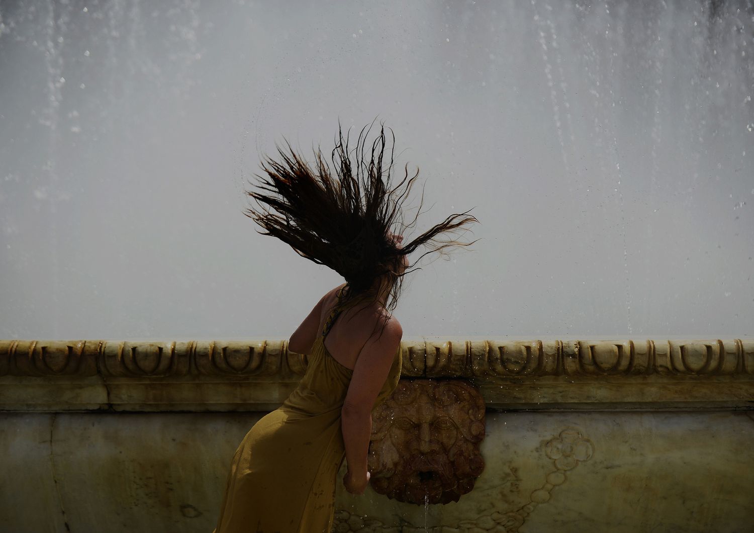 Una donna cerca refrigerio in una fontana di Plaza de Espana, a Siviglia&nbsp;