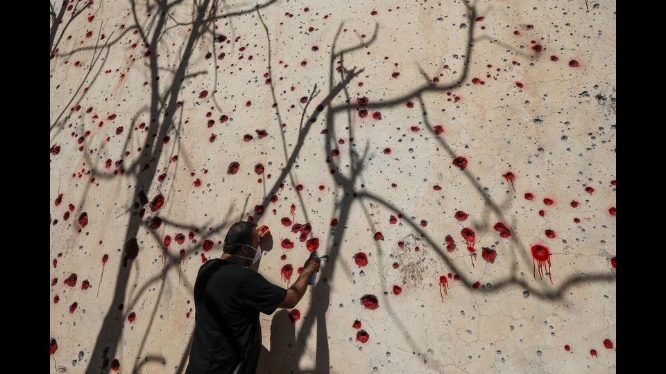 Un membro peshmerga curdo-iraniano del Partito democratico iraniano del Kurdistan (KDPI) spruzza vernice rossa nei buchi di un muro fatto dalle schegge provocate da un attacco di razzi nei giorni scorsi presso la sede del partito a Koysinjaq, 100 chilometri a est della capitale del nordico curdo iracheno regione autonoma di Arbil, il 12 settembre 2018. Almeno una dozzina di membri del gruppo ribelle curdo iraniano sono stati uccisi l'8 settembre nell'attacco missilistico al loro quartier generale effettuato dal rivoluzionario iraniano