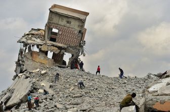 Un gruppo di persone recupera materiale da costruzione il 13 settembre 2018, in un sito di demolizione con macerie precariamente inclinate, dopo che i bulldozer governativi hanno abbattuto un centro commerciale accusato di essere illegale per essere stato costruito su un letto del fiume nella capitale del Kenya, Nairobi.TONY KARUMBA / AFP