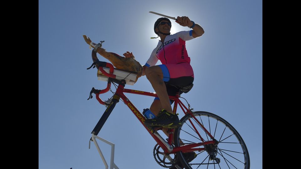 Un uomo taglia un pezzo di prosciutto iberico seduto su una bicicletta in cima a un furgone mentre aspetta la 18a tappa della 73a edizione della corsa ciclistica &quot;La Vuelta&quot; del Tour della Spagna, un percorso di 186,1 km da Ejea de los Caballeros a Lleida il 13 settembre 2018.
