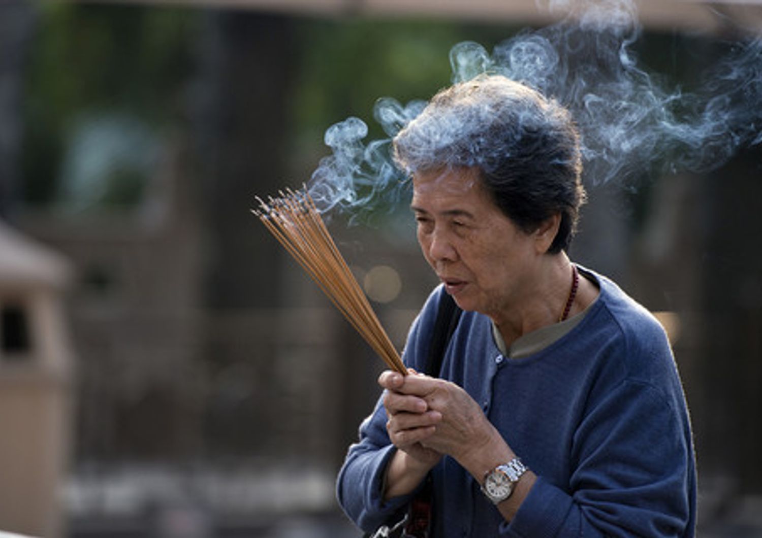 A woman prays holding incense sticks at the Wong Tai Sin temple in Hong Kong on October 28, 2013. The Taoist temple is a major tourist attraction and centre for worship in Hong Kong, and attracts thousands of visitors each year especially around the Chinese New Year holiday.