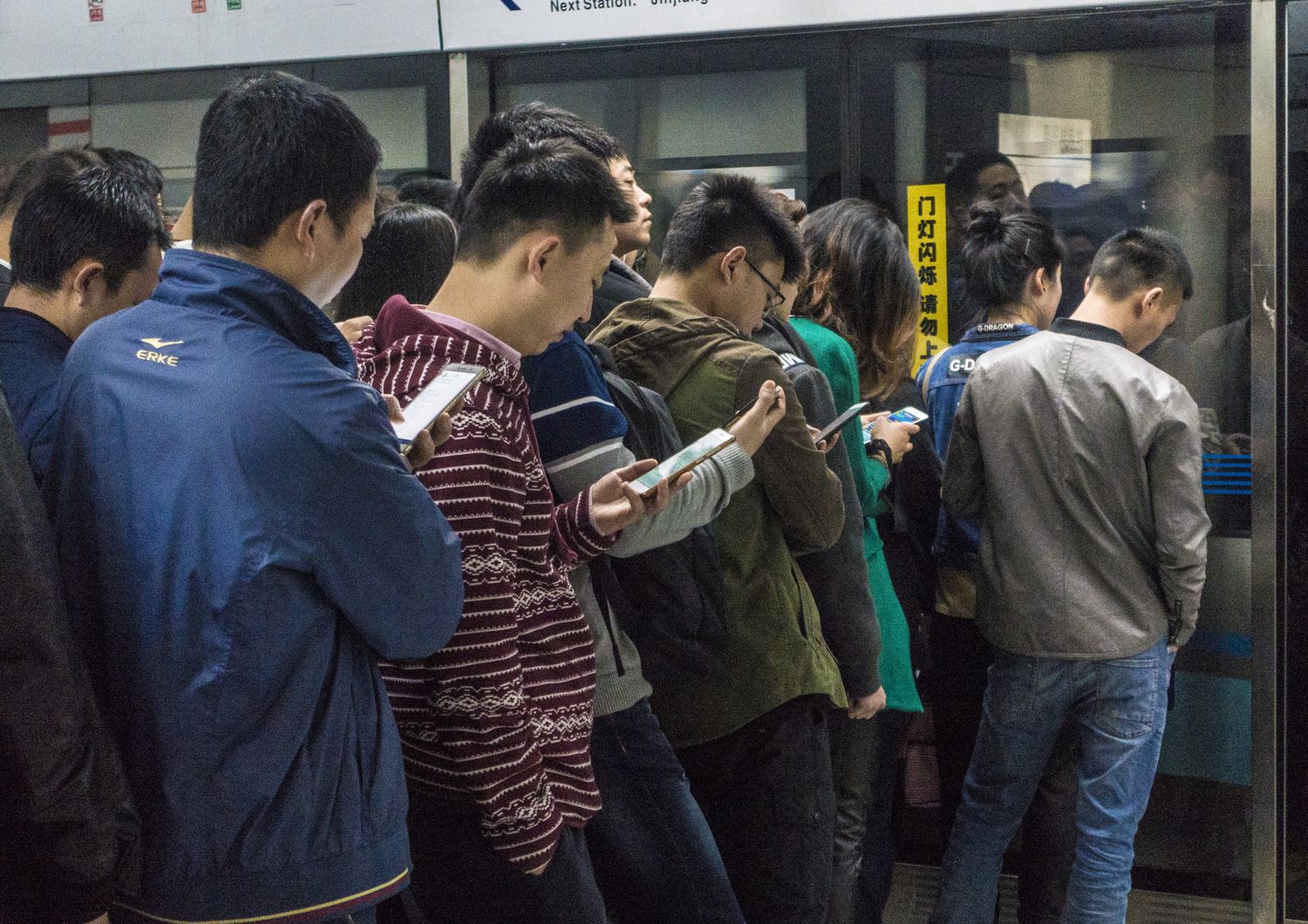 Persone che guardano il cellulare in attesa di entrare nella metro di Pechino&nbsp;