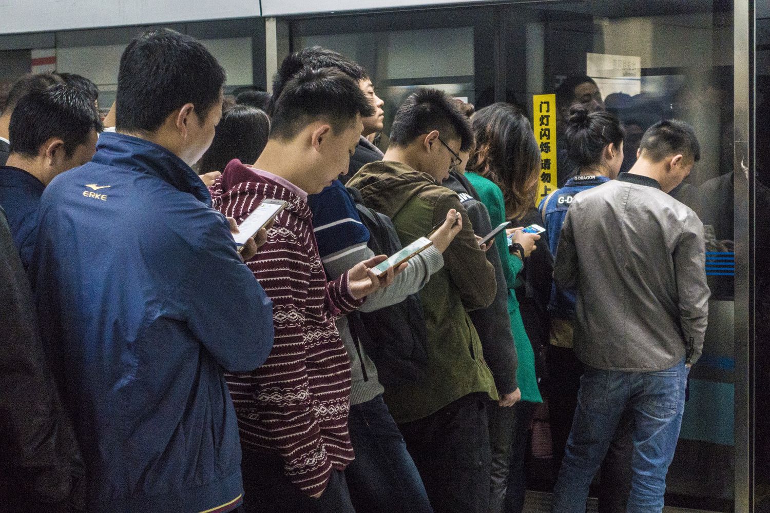 Persone che guardano il cellulare in attesa di entrare nella metro di Pechino&nbsp;