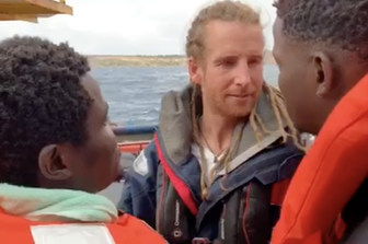 Un volontario della Sea Watch&nbsp;saluta i migranti prima dello sbarco