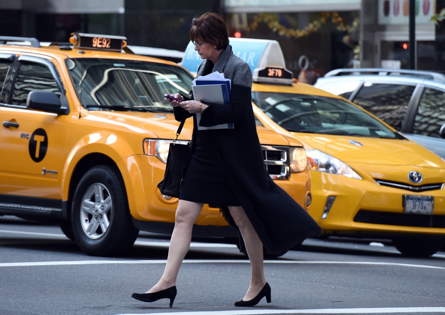 Una donna attraversa la strada di New York scrivendo al cellulare