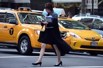 Una donna attraversa la strada di New York scrivendo al cellulare