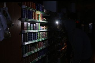 Un cliente si fa luce con uno smartphone tra gli scaffali di un supermercato di Buenos Aires durante il blackout