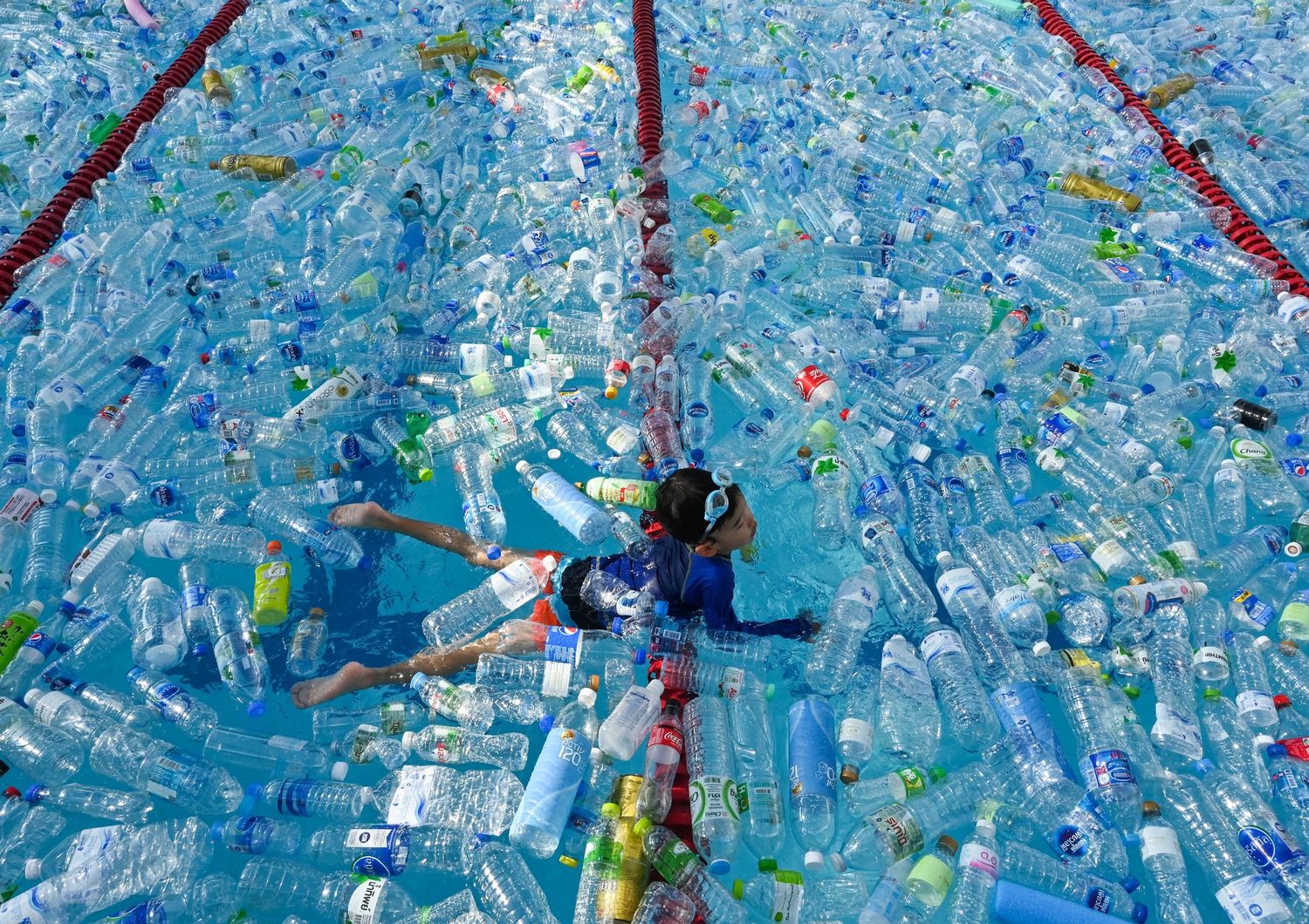 Un bambino nuota in una piscina piena di plastica: parte di una campagna contro l'Inquinamento a Bangkok