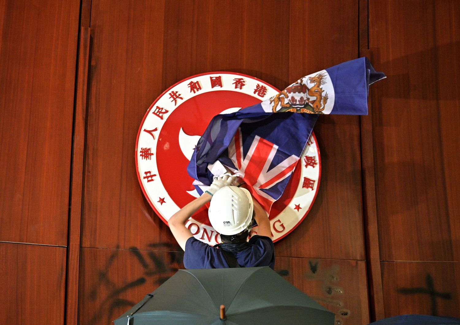 Manifestanti nel Parlamento di Hong Kong issano sul muro dell'aula la bandiera coloniale britannica