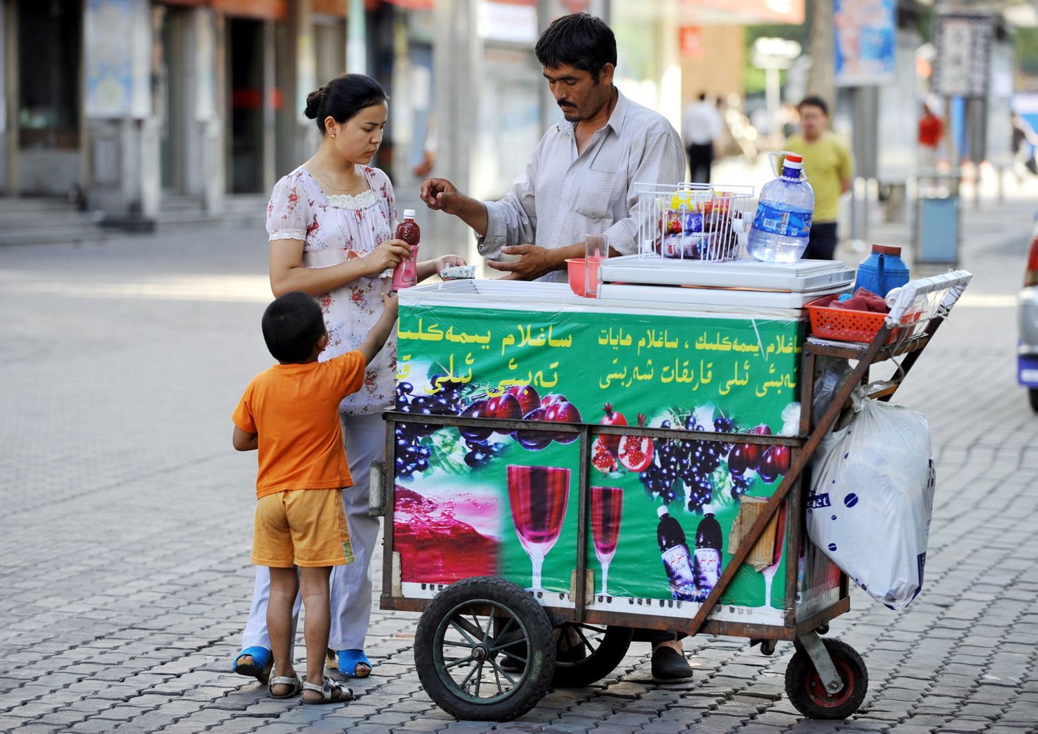 Una donna compra una bottiglia d'acqua da un venditore di strada&nbsp;a Urumqi, citt&agrave; a nordest dello Xinjiang, Cina