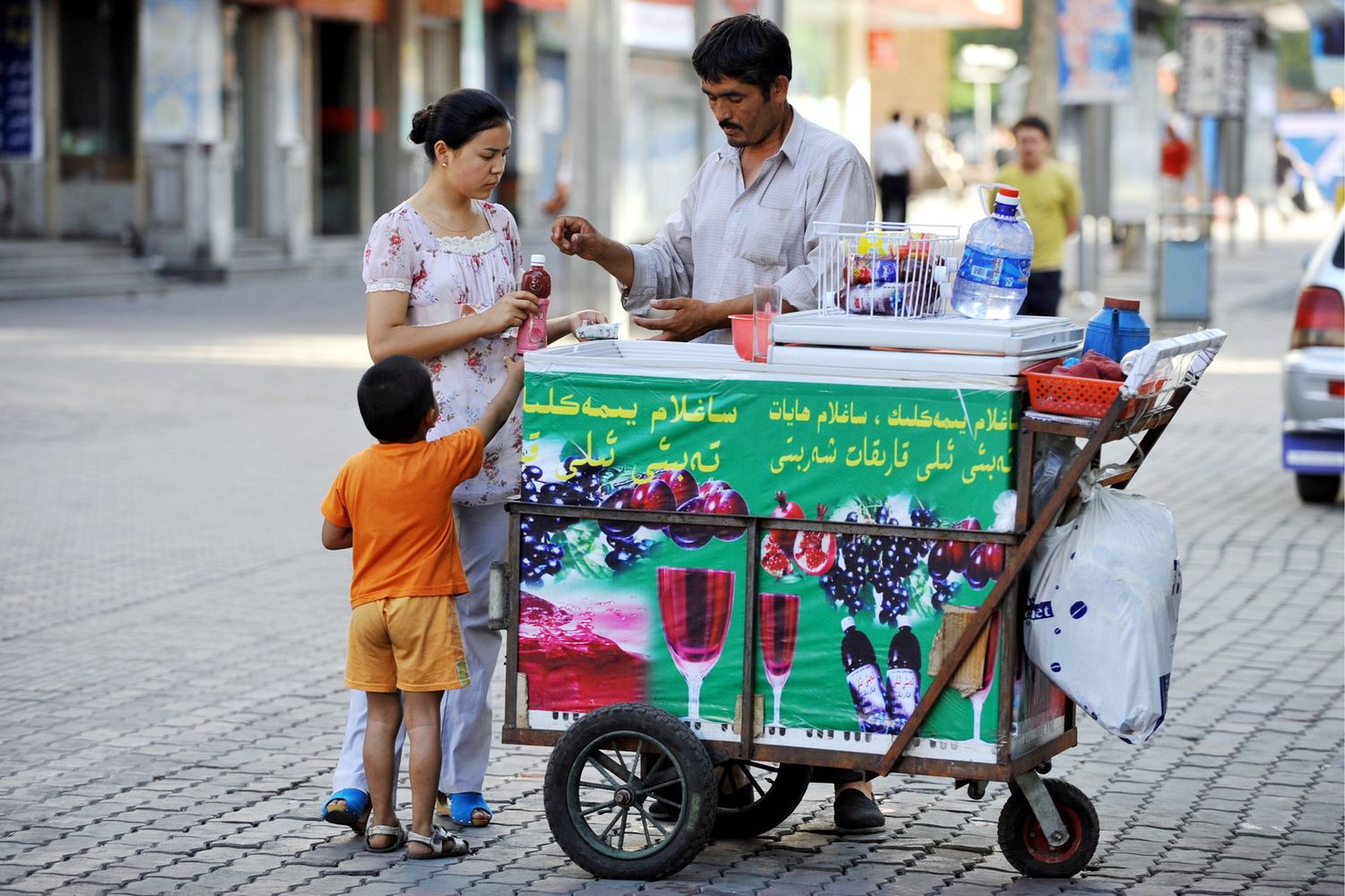 Una donna compra una bottiglia d'acqua da un venditore di strada&nbsp;a Urumqi, citt&agrave; a nordest dello Xinjiang, Cina