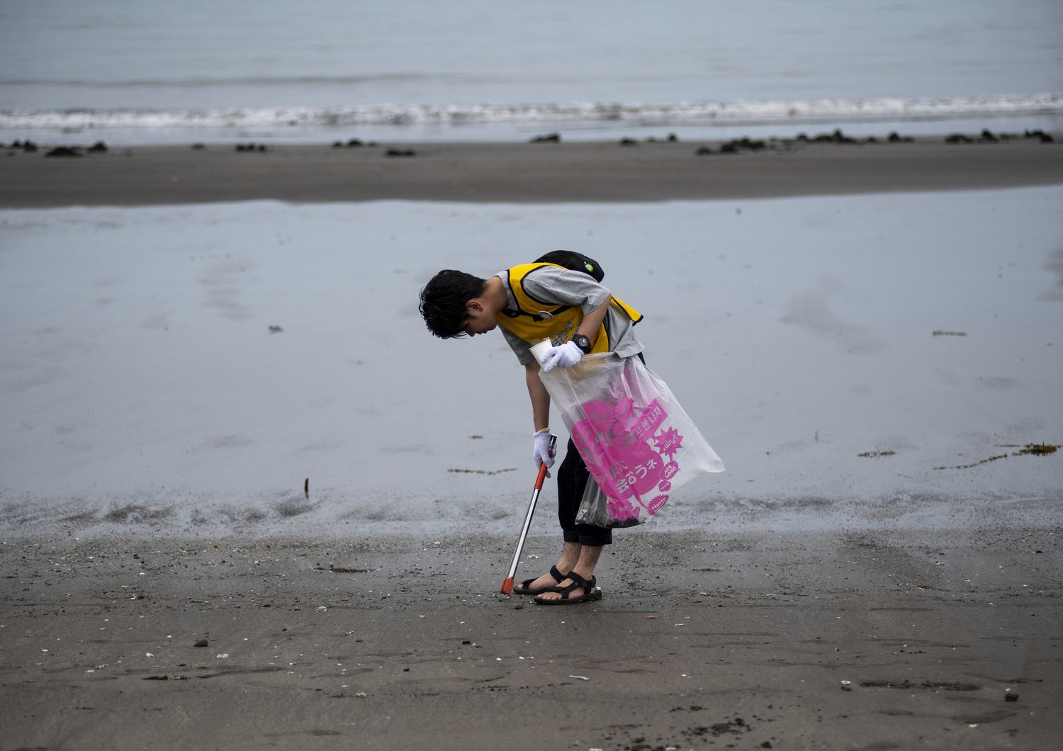 Un ragazzo raccoglie plastica su una spiaggia del Giappone