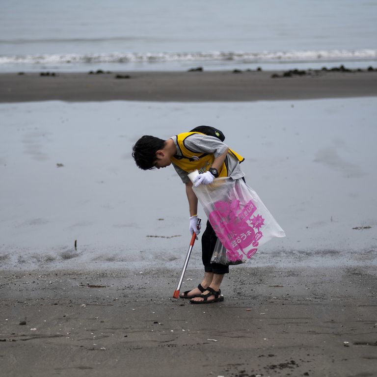 Un ragazzo raccoglie plastica su una spiaggia del Giappone