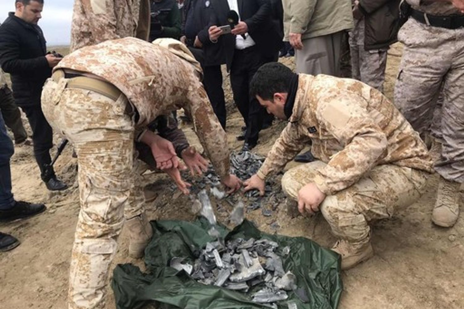 Militari iracheni raccolgono pezzi di uno dei missili iraniani sparati contro la base aerea di Erbil