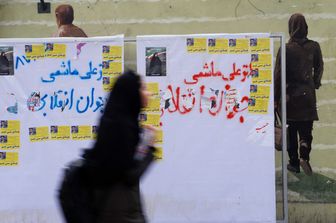 Una donna cammina davanti ai manifesti elettorali a Teheran