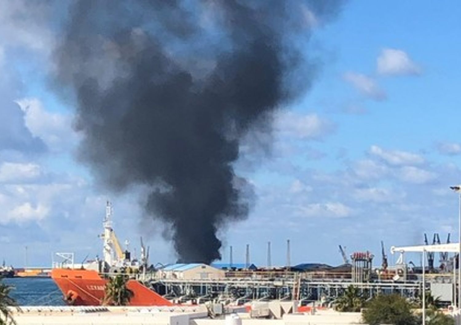 Una colonna di fumo nero si alza dal porto di Tripoli bombardato