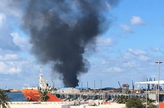 Una colonna di fumo nero si alza dal porto di Tripoli bombardato