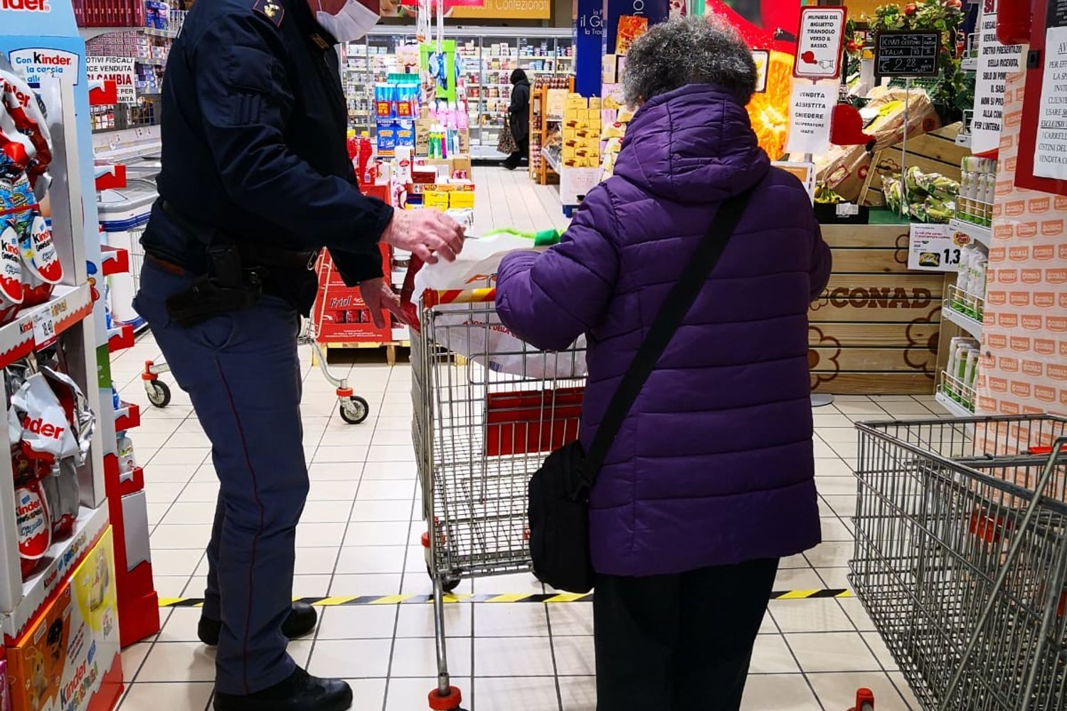 Un agente di polizia aiuta un'anziana con la spesa durante il blocco deciso per il coronavirus