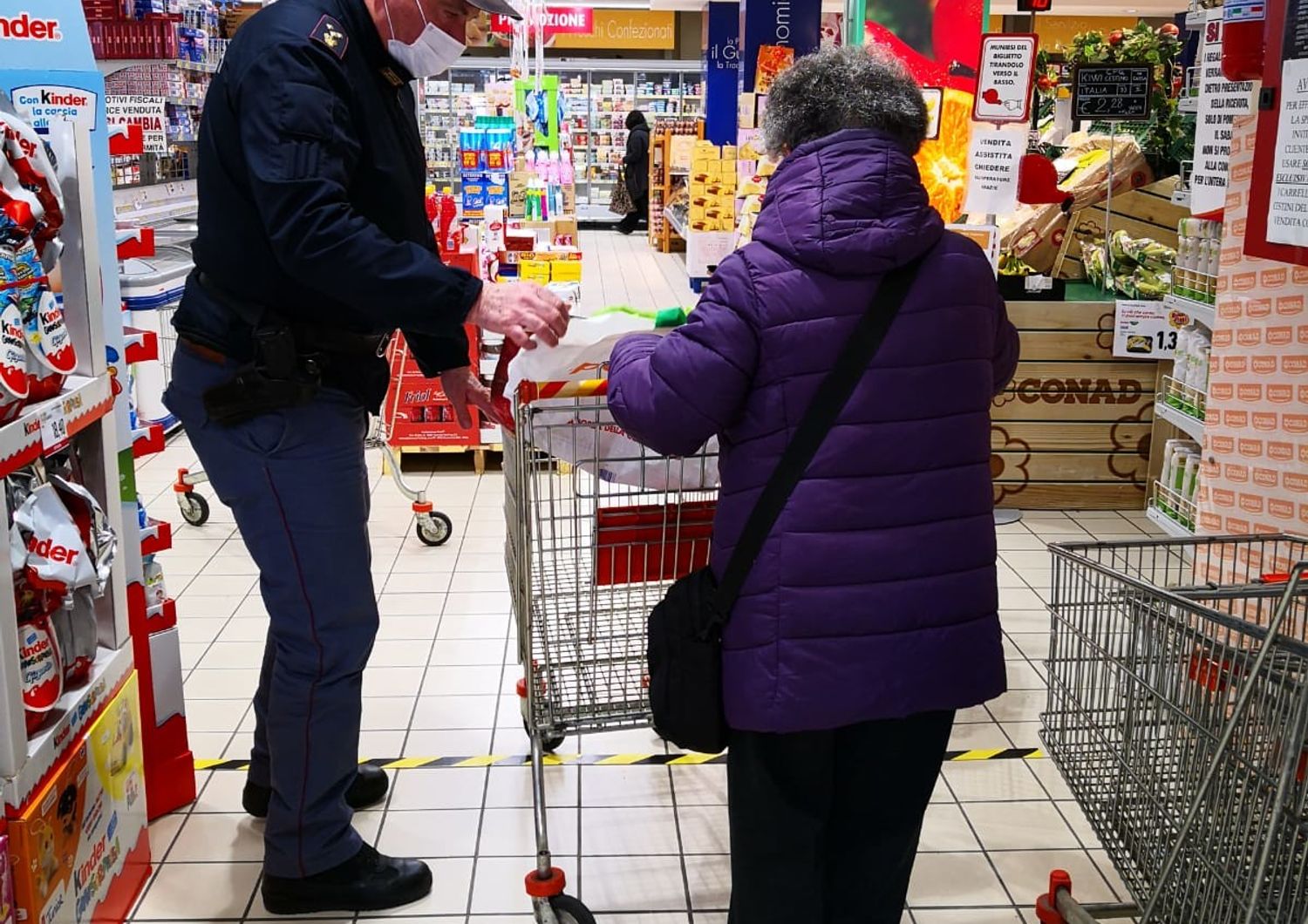 Un agente di polizia aiuta un'anziana con la spesa durante il blocco deciso per il coronavirus