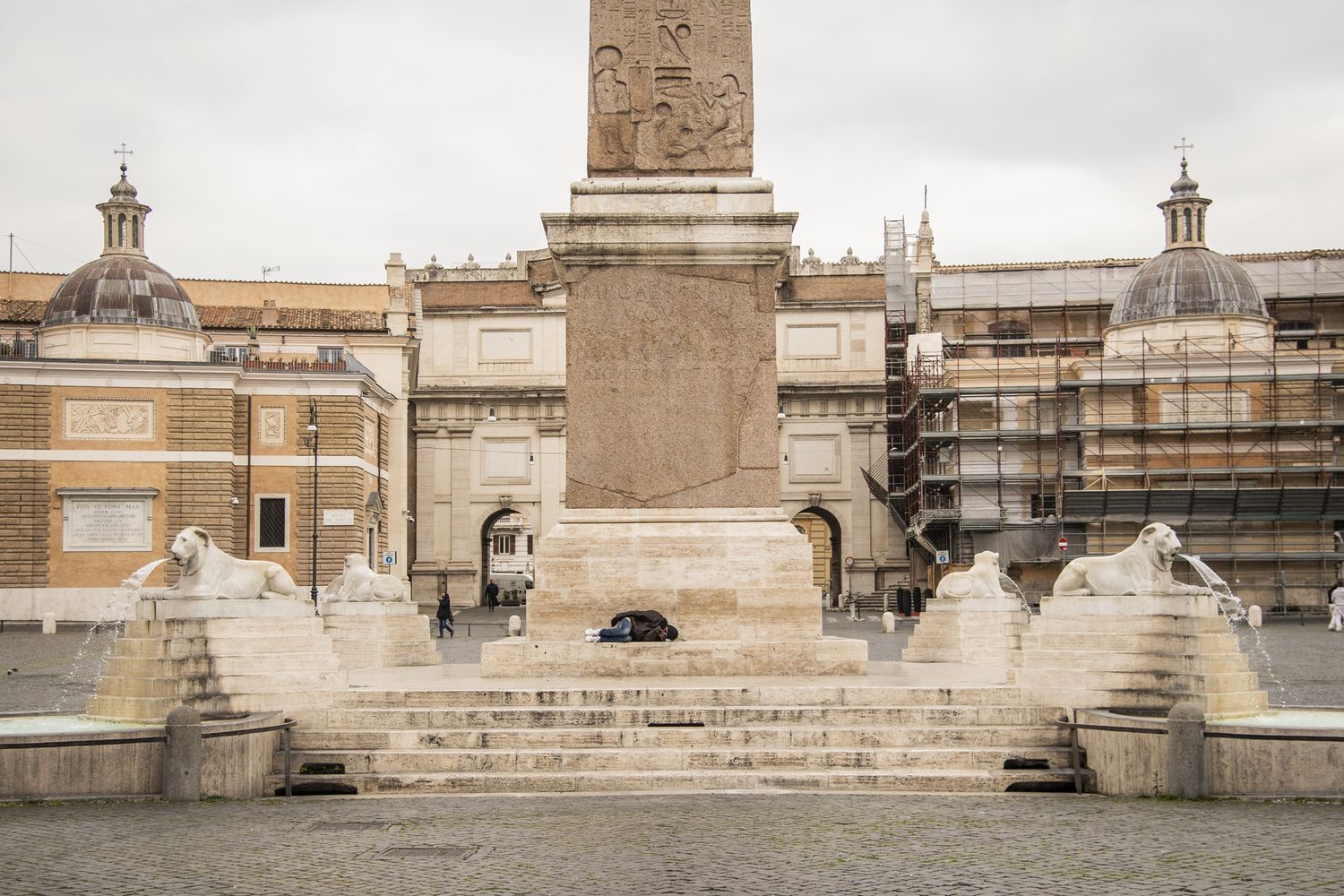 Un clochard dorme in una Piazza del Popolo deserta