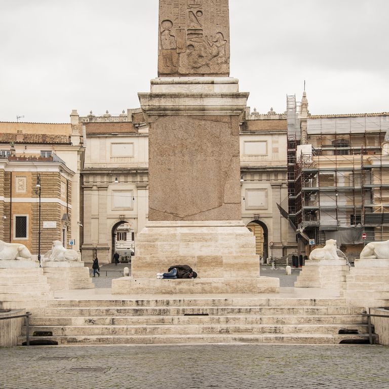 Un clochard dorme in una Piazza del Popolo deserta