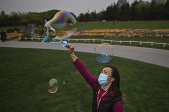 Una donna fa le bolle di sapone in un parco di Shanghai