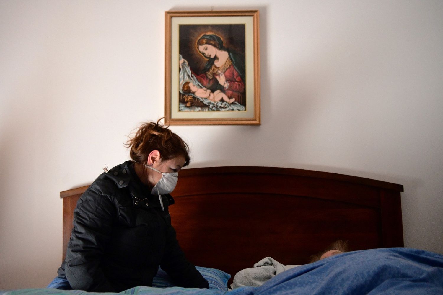 Una donna al capezzale della madre malata di coronavirus