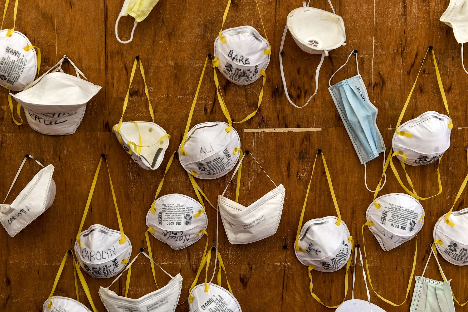 Le mascherine appese in un ospedale italiano portano i nomi dei medici che sono costretti a riutilizzarle