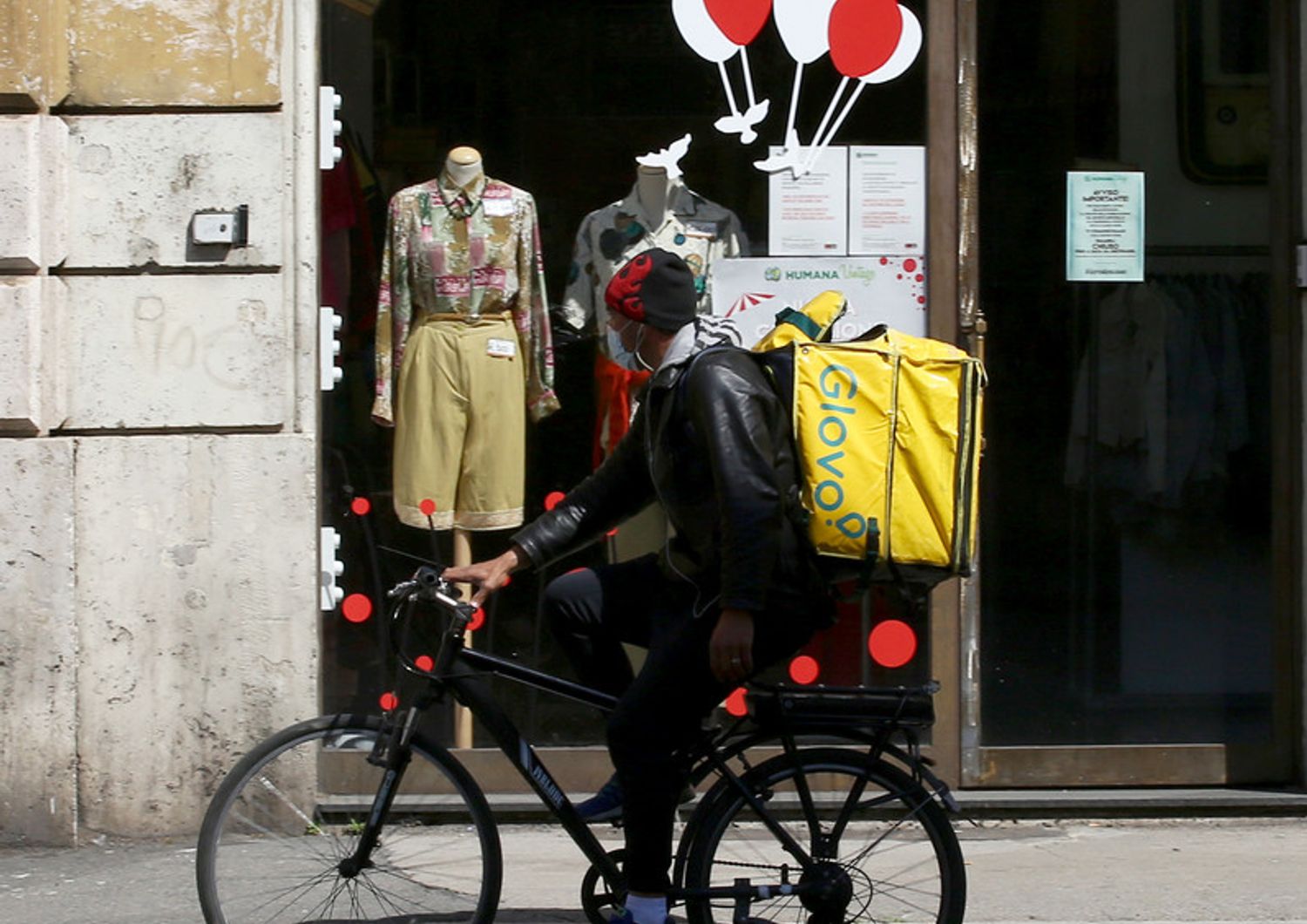 Un rider passa davanti a un negozio di abbigliamento chiuso nel centro di Roma