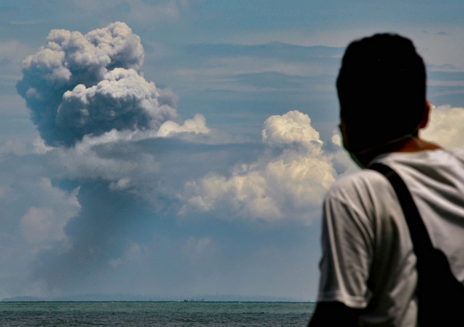 Un uomo osserva la colonna di cenere del vulcano Anak Krakatau dalla citt&agrave; indonesiana di Serang