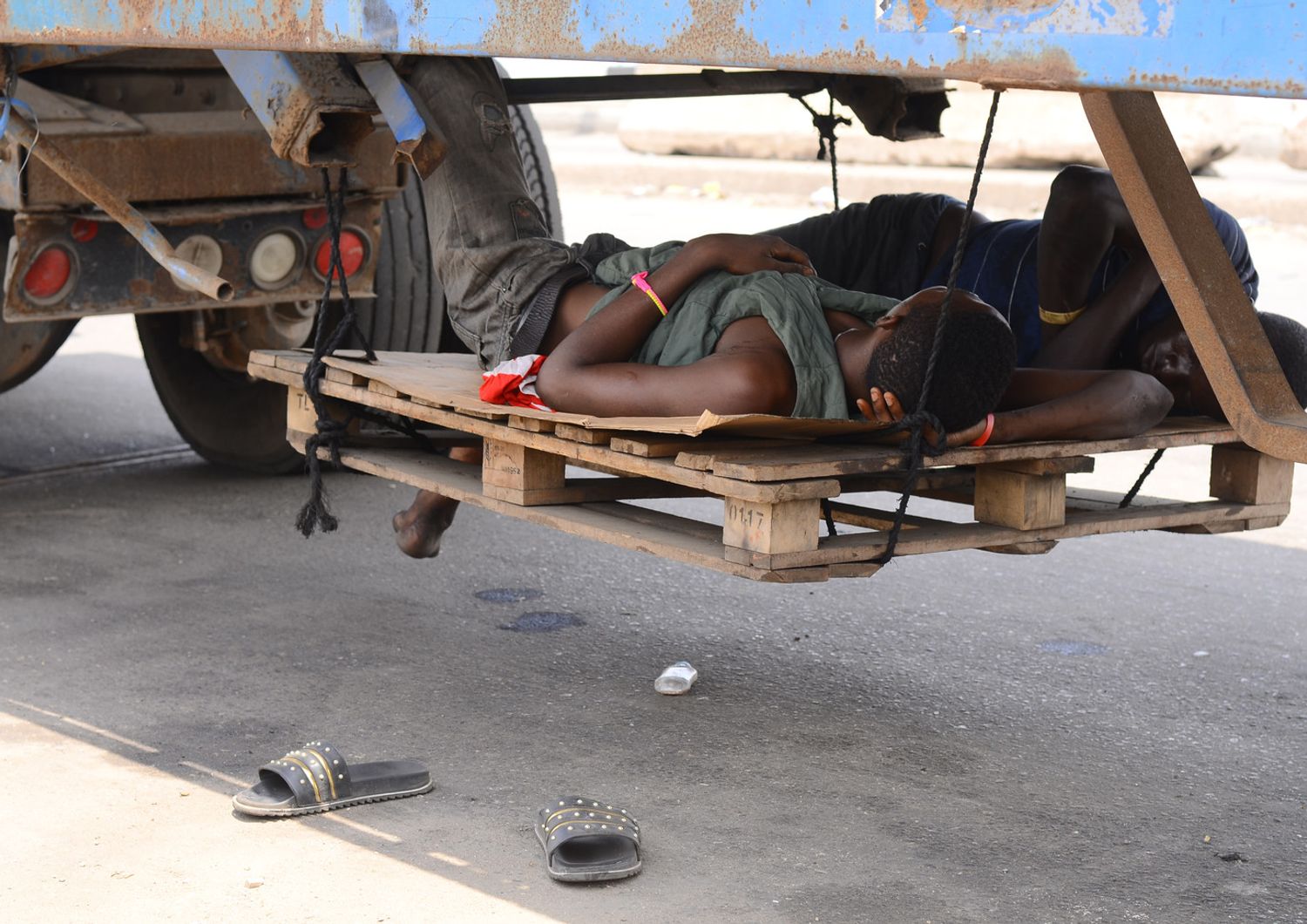 Camionisti si riposano sotto un rimorchio nel porto di Apapa a Lagos, in Nigeria