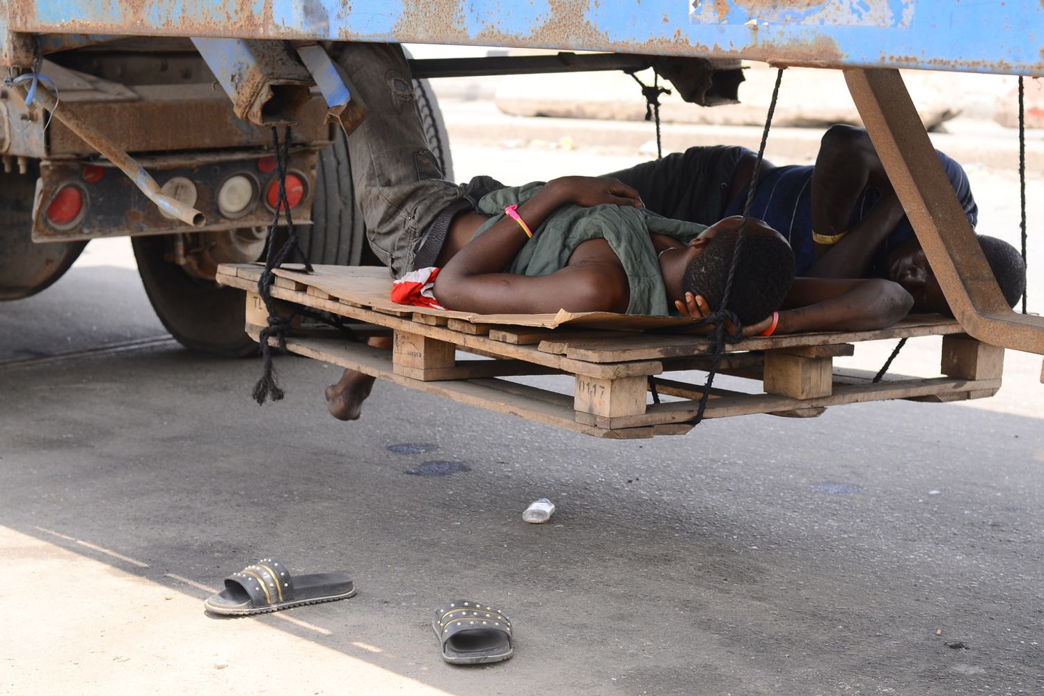 Camionisti si riposano sotto un rimorchio nel porto di Apapa a Lagos, in Nigeria