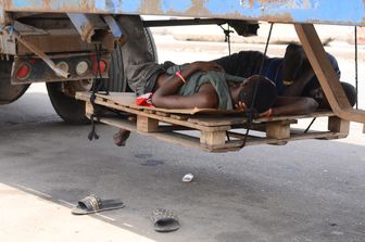 Camionisti si riposano sotto un rimorchio nel porto di Apapa a Lagos, in Nigeria