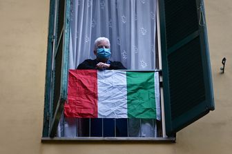 Un anziano con la mascherina protettiva contro il coronavirus sul balcone di casa a Roma
