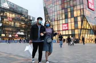 Una coppia a passeggio nel centro di Pechino con le mascherine contro il coronavirus