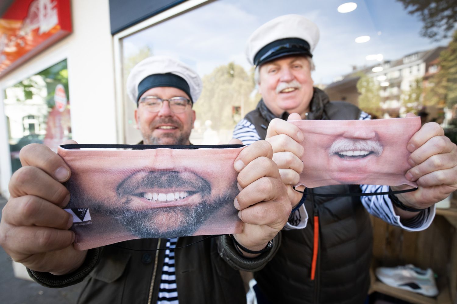 I musicisti Klaus &amp; Klaus mostrano le mascherine con il loro volto stampate i un negozio di Berlino