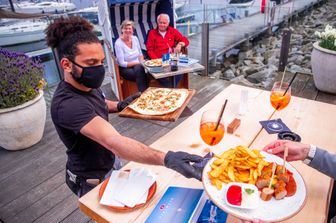 Un cameriere serve un piatto di carne in un ristorante appena riaperto a Kuehlungsborn, in Germania