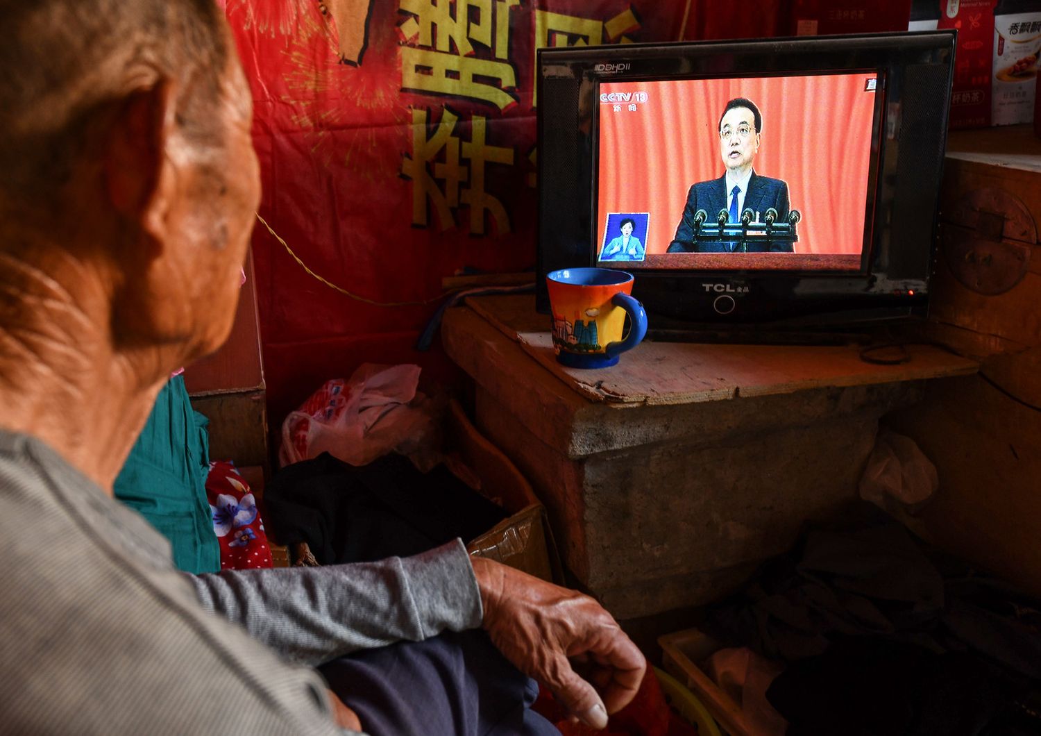 Un uomo ascolta in tv il discorso del il premer cinese Li Keqiang