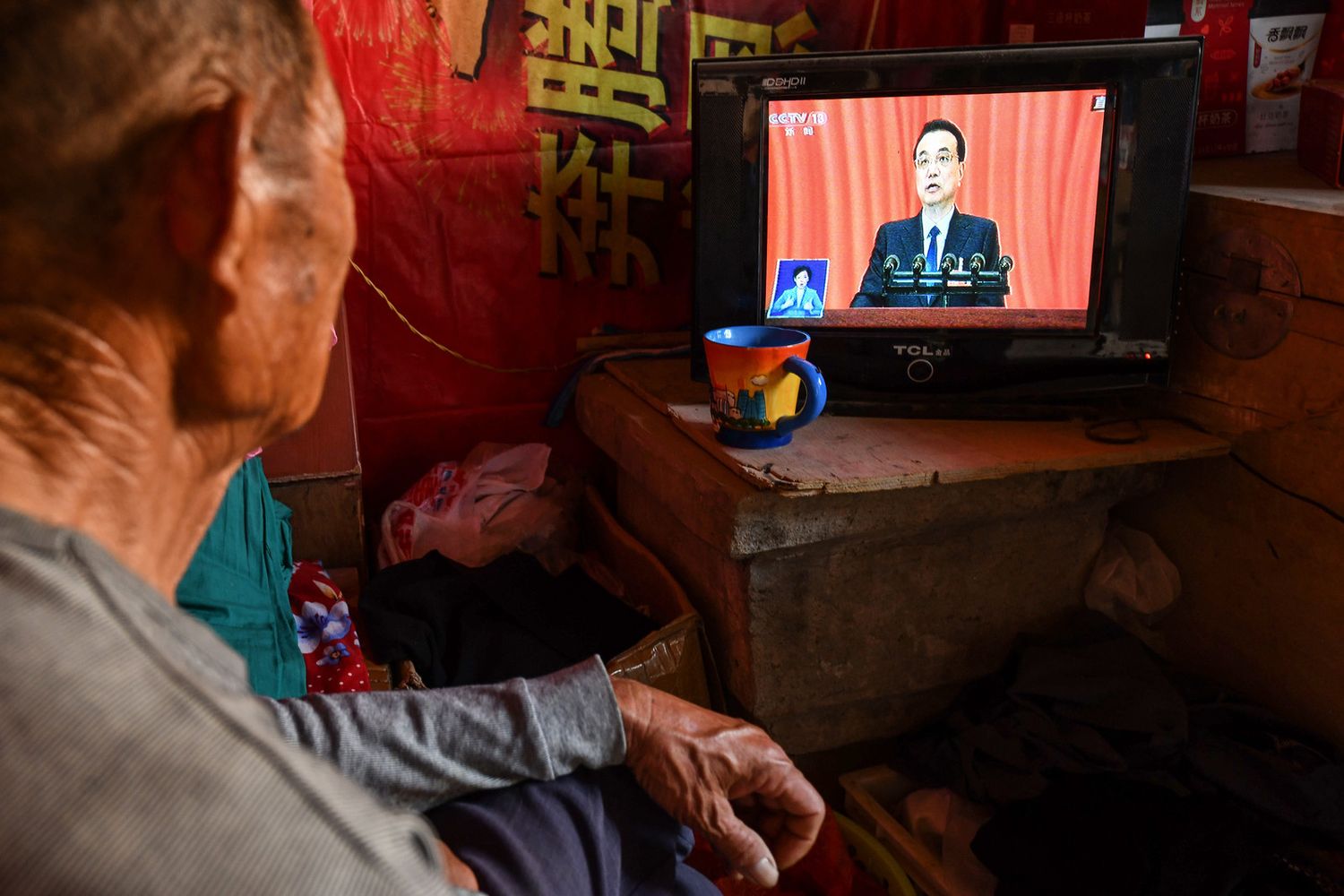 Un uomo ascolta in tv il discorso del il premer cinese Li Keqiang