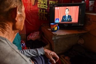 Un uomo ascolta in tv il discorso del il premer cinese Li Keqiang