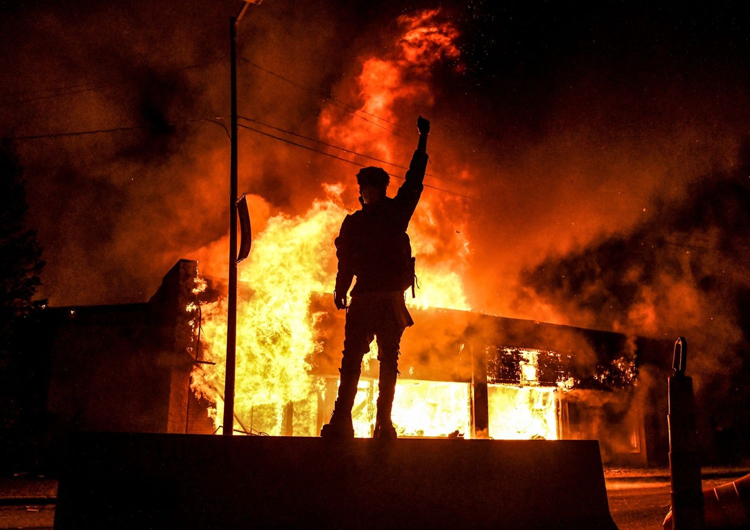 Un manifestante di fronte a un edificio in fiamme a Minneapolis