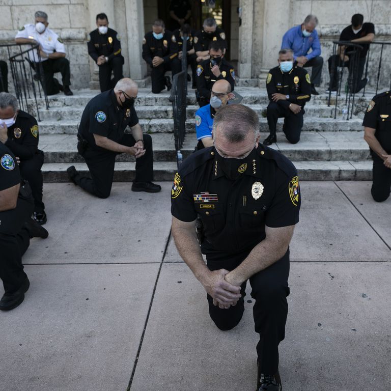 Agenti di polizia di Coral Gables, nella contea di Maiami Dade, pregano con i manifestanti