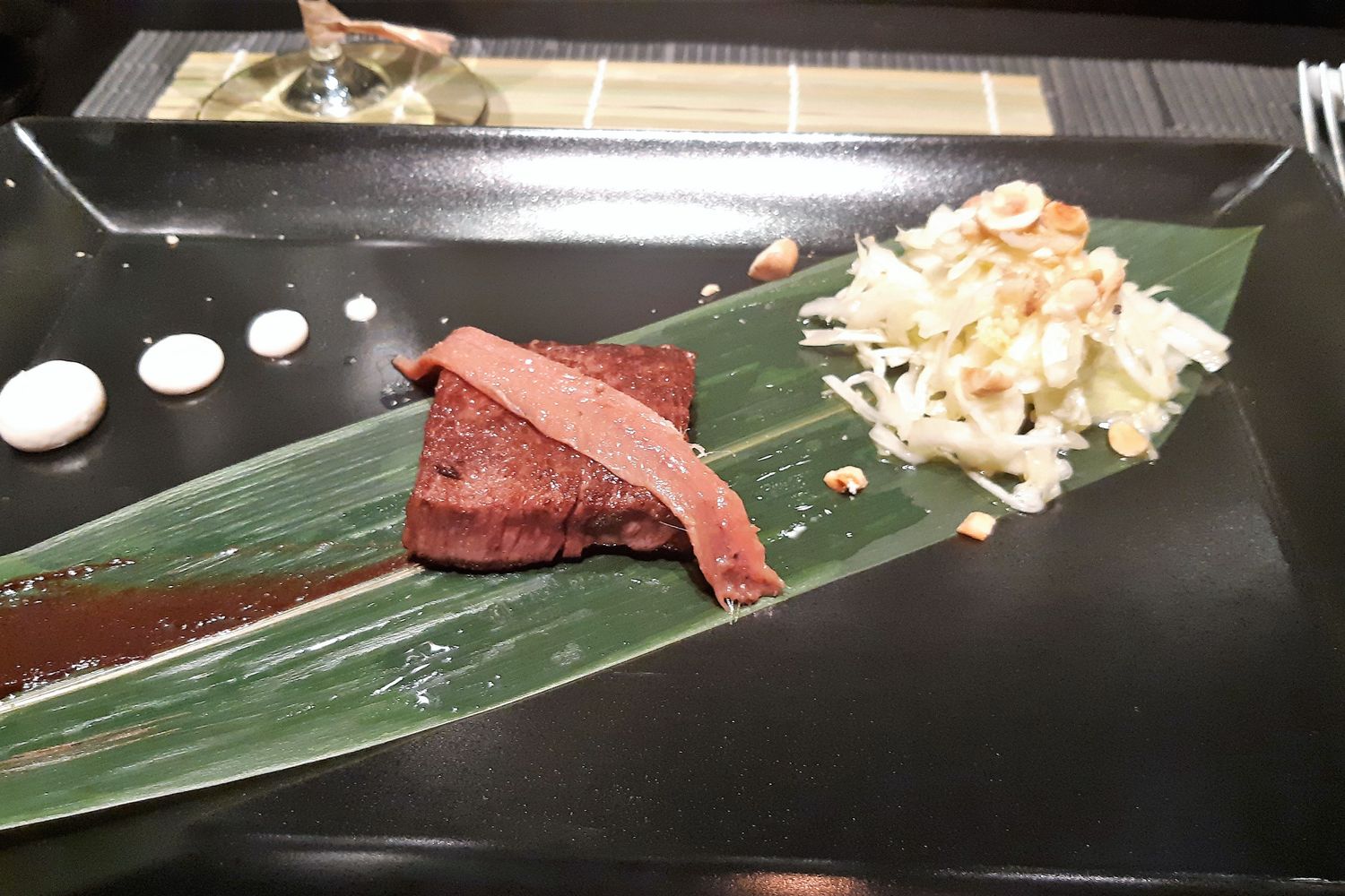 Carne Wagyu in abbinamento con acciuga servita con una purea di aglio nero di Voghera, una insalata di verza condita con un olio acciughe, alghe e nocciole&nbsp;