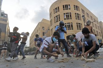 Manifestanti raccolgono sassi da lanciare durante la manifestazione a Beirut