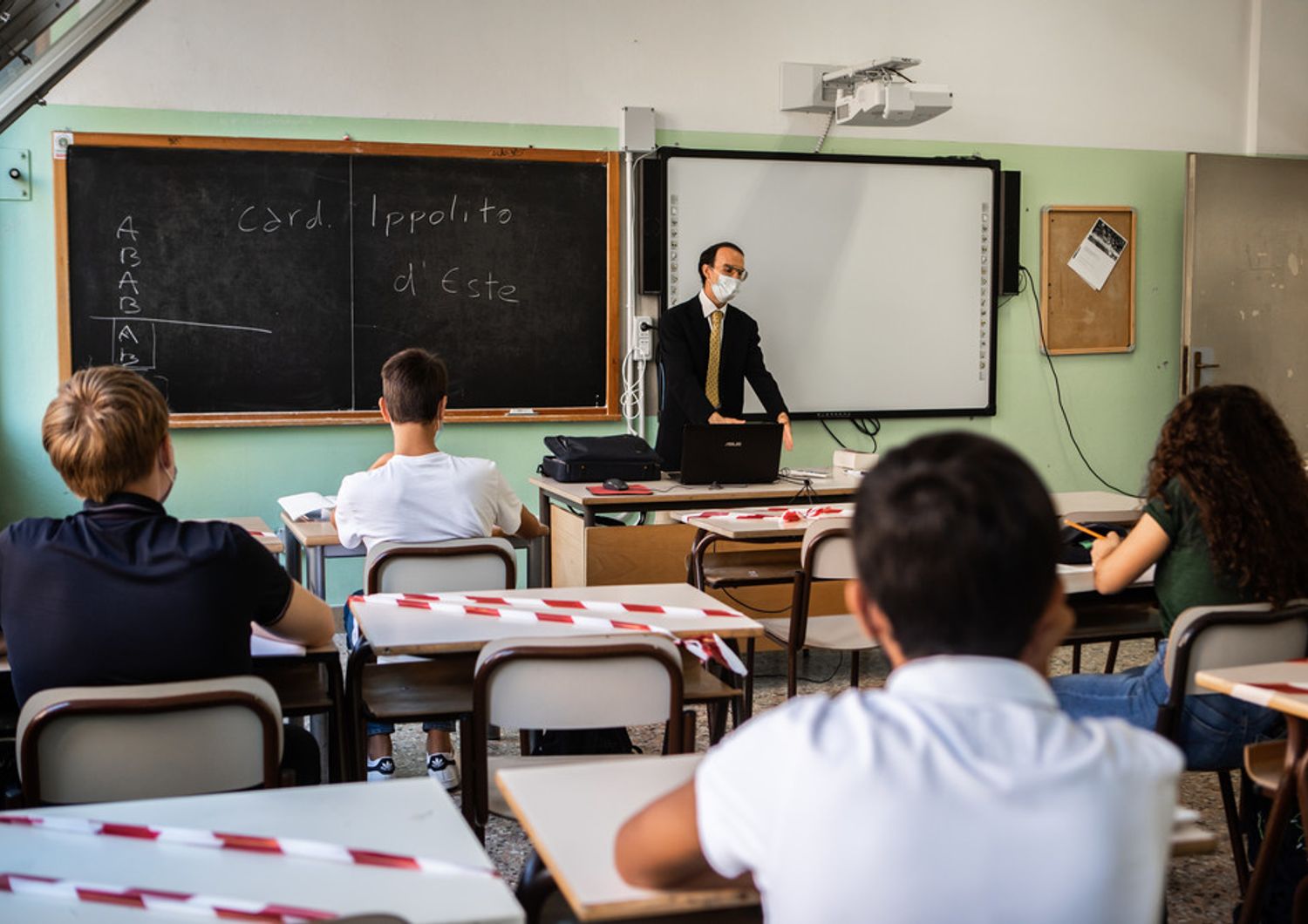 Insegnante a scuola con mascherine e distanziamento