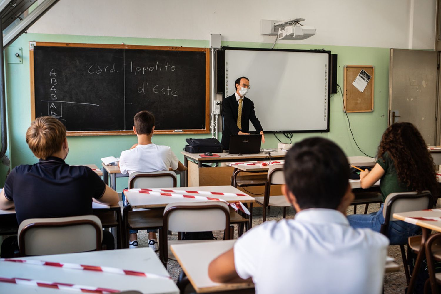 Insegnante a scuola con mascherine e distanziamento